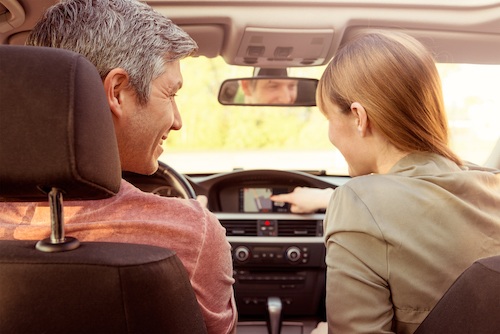 woman in car helping smiling man navigate