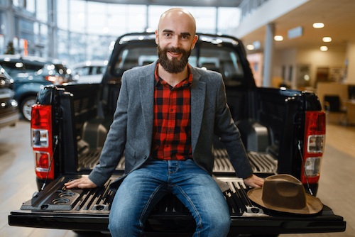 Man sitting in the back of truck, car dealership
