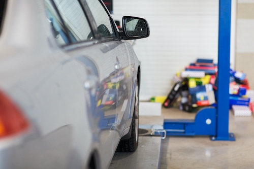 silver car on lift at auto repair shop
