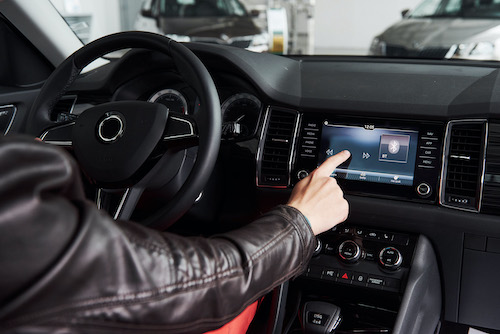 man in smart car touching electric dashboard