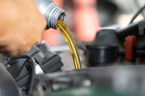 mechanic-pouring-motor-oil-into-a-car-engine mechanic-pouring-motor-oil-into-a-car-engine
